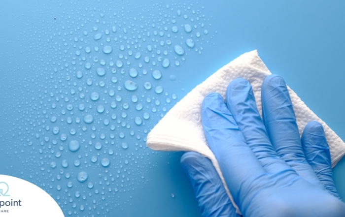 A gloved hand wipes down a surface, representing hygiene and practices that home health workers should employ.