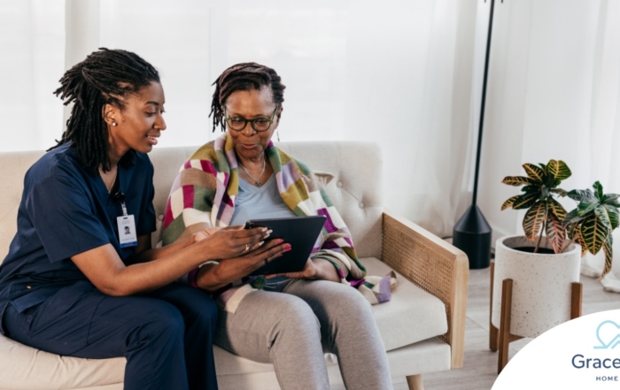 A caregiver talks with a patient while showing her information on a tablet representing the type of thorough communication needed for effective and professional care of home health care patients.