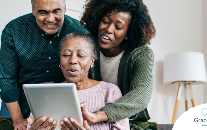 A daughter looks at a tablet with her older parents, representing technology and how ti can help with aging in place.