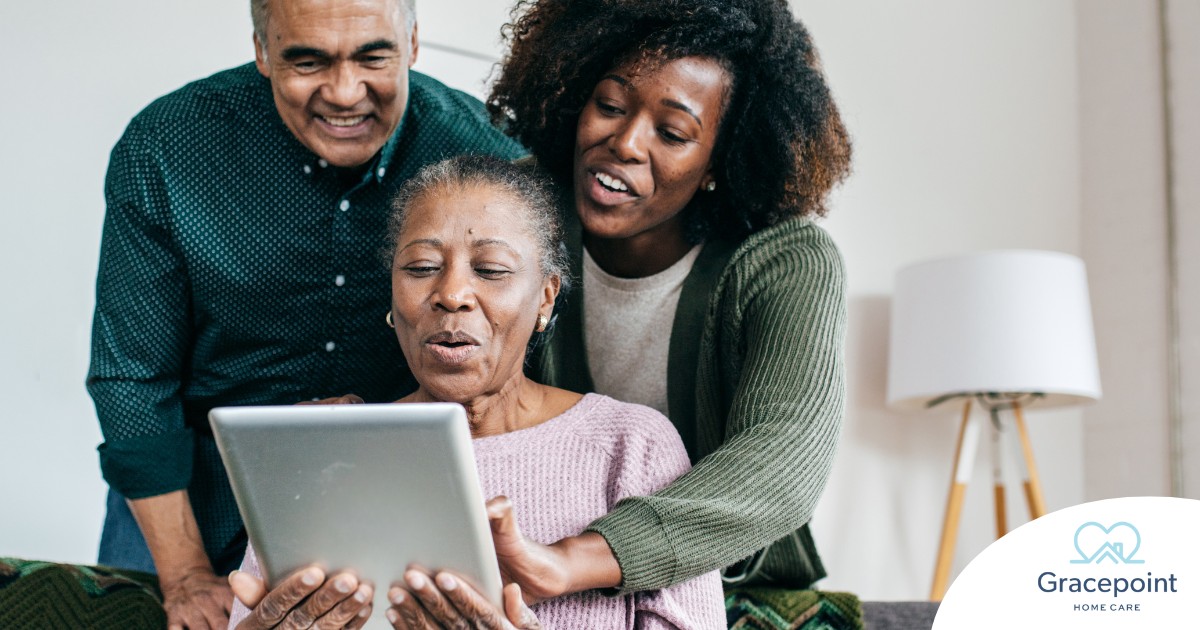A daughter looks at a tablet with her older parents, representing technology and how ti can help with aging in place.