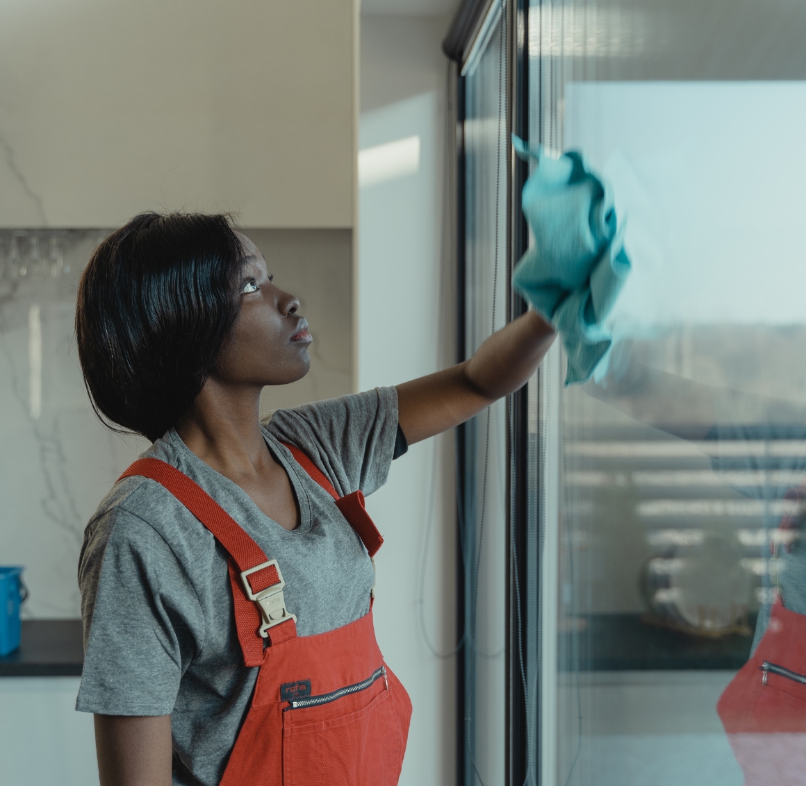 A woman cleaning the windows of a bright, tidy living room, representing light housekeeping in Gulf Shores.