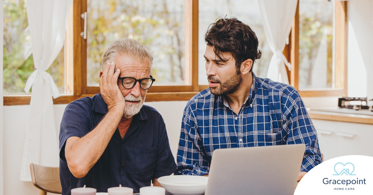 A man looks at a computer with his father who is confused, representing one of the early signs of dementia.