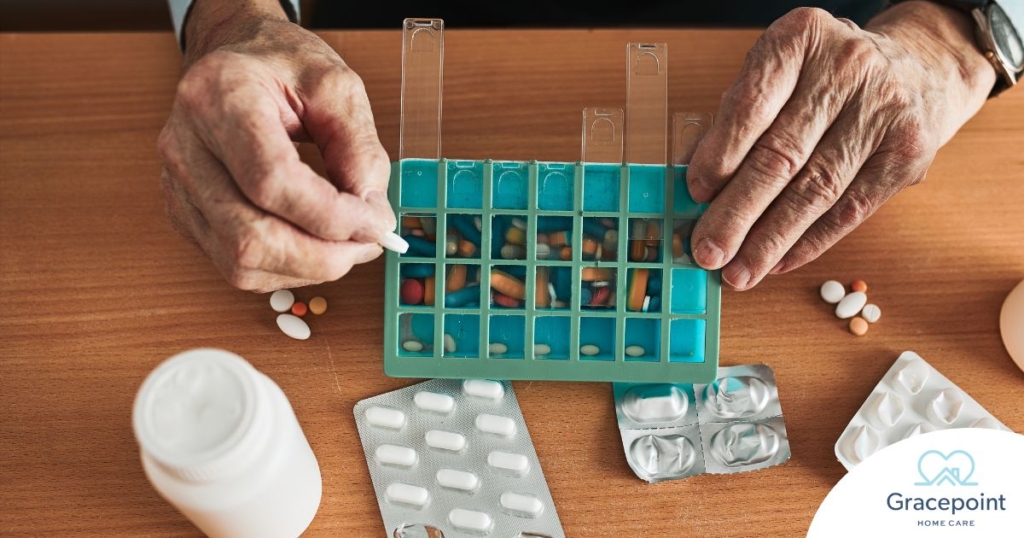 Older hands organize pills into a pill organizer, showing a great tool for managing medications.