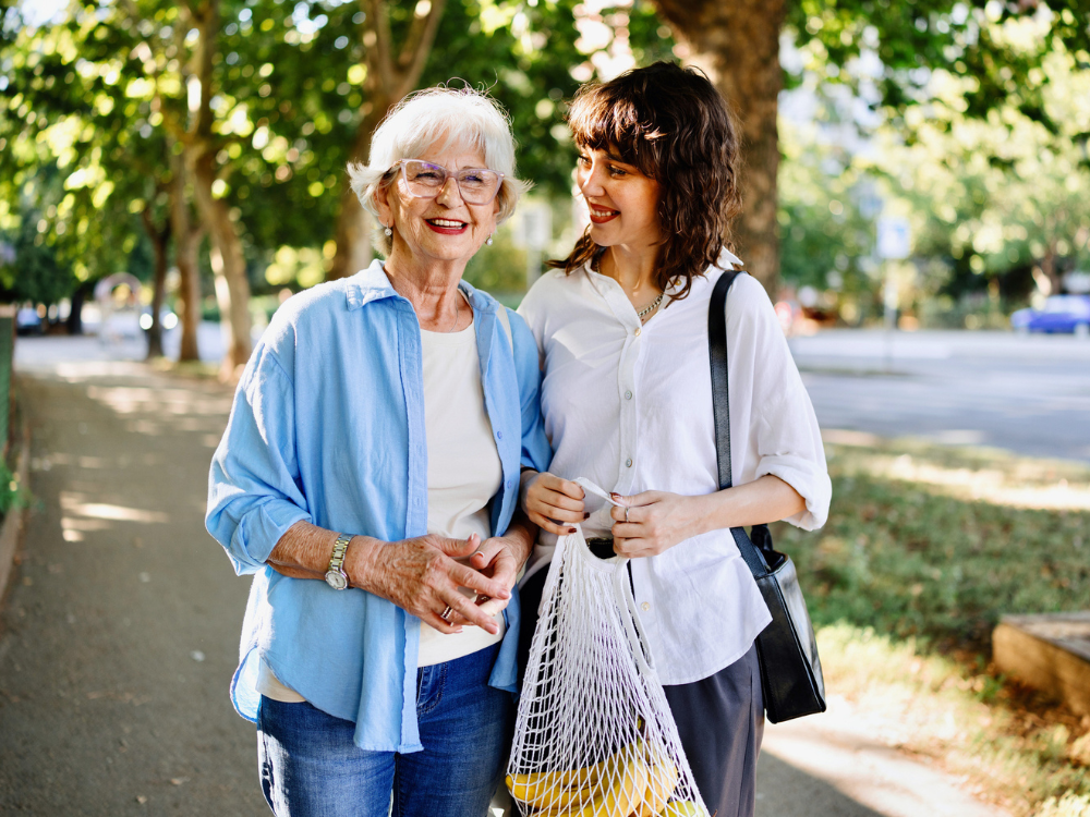 Senior woman walking outdoors with her daughter, symbolizing connection and peace of mind through GraceLink Care Connect by Gracepoint Home Care.